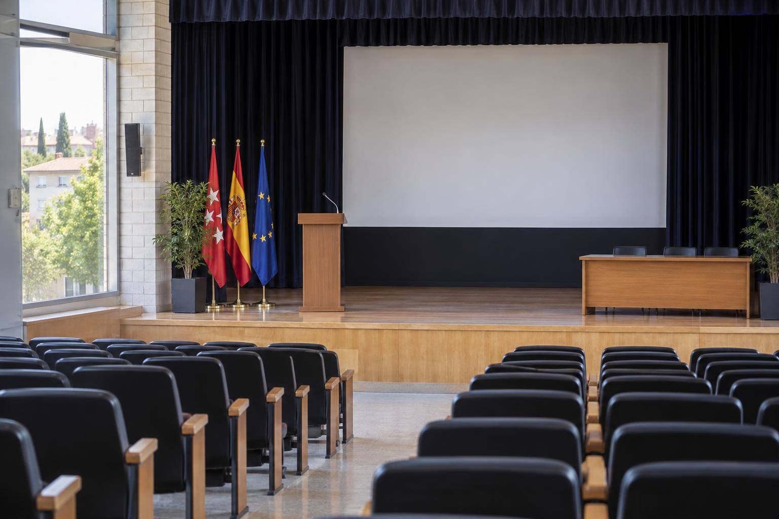 Imagen ilustrativa: Salón de actos de un instituto con un atril y filas de butacas, sin personas reconocibles