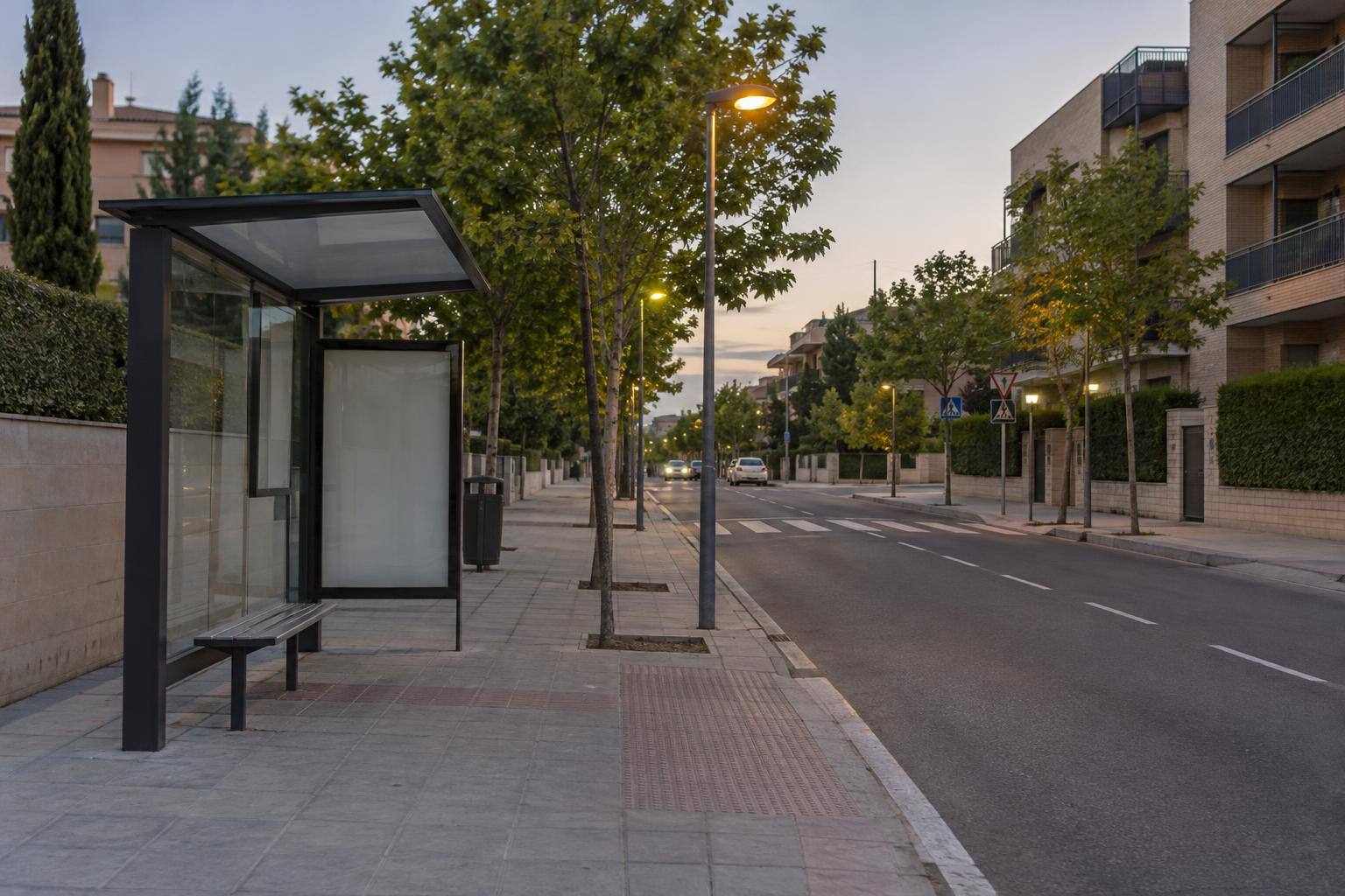 Imagen ilustrativa: Calle urbana con alumbrado público, una parada de autobús y arbolado, sin personas reconocibles.
