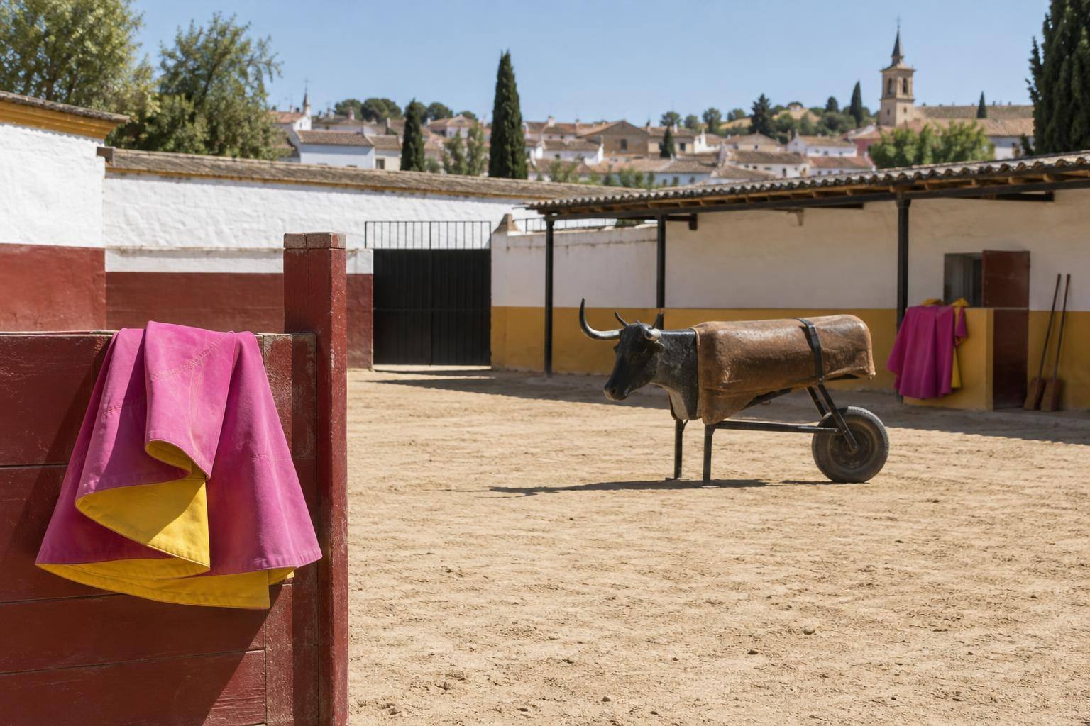 Imagen ilustrativa: Patio de entrenamiento de una escuela de tauromaquia con capotes y un carretón de prácticas, sin personas