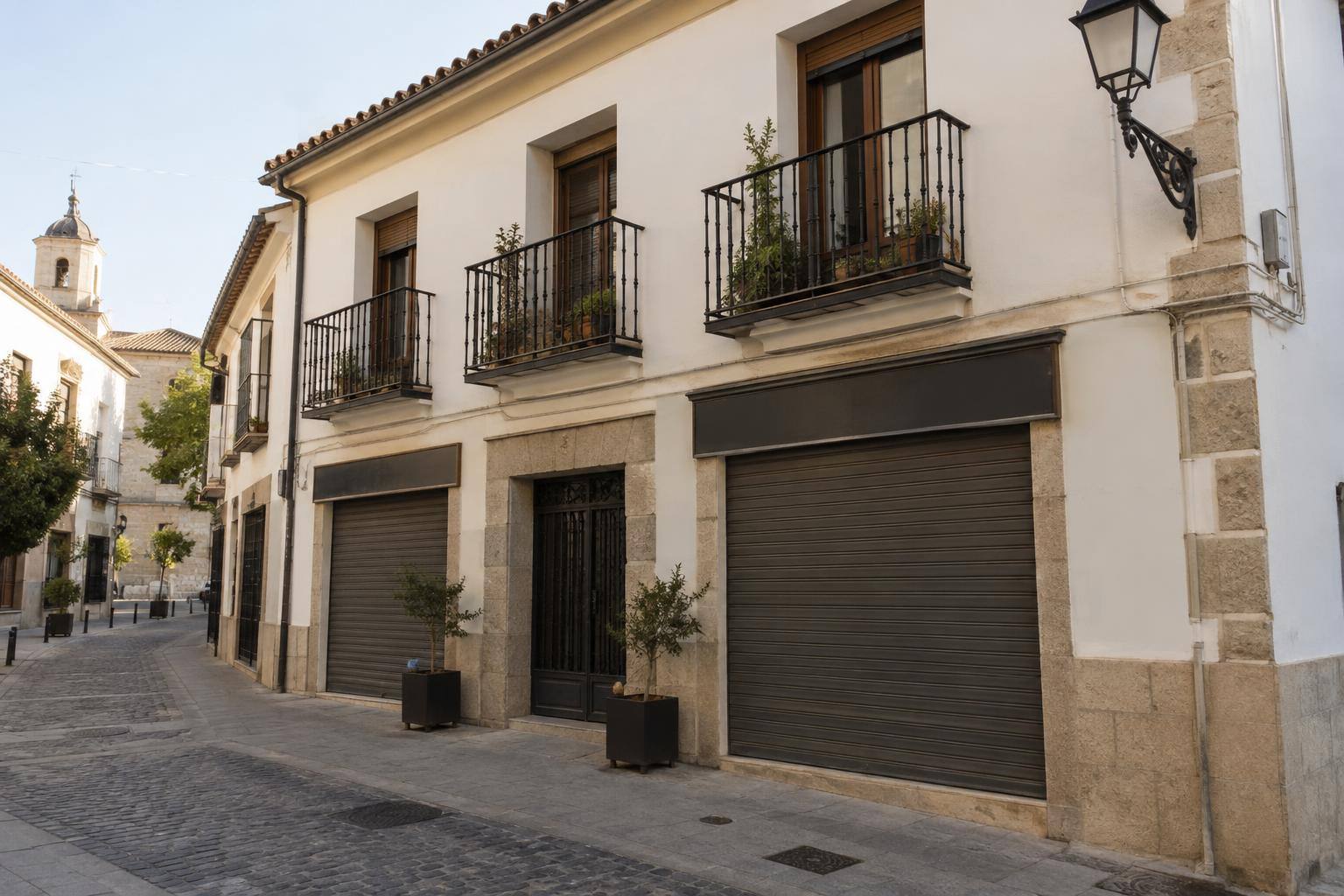 Imagen ilustrativa: Fachada de un edificio residencial de dos plantas con locales cerrados en la planta baja, en una calle de un casco histórico andaluz, sin personas reconocibles.