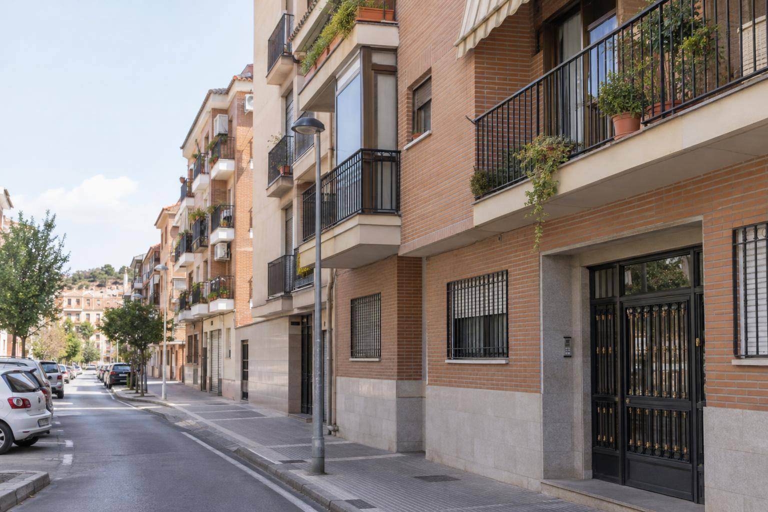 Imagen ilustrativa: fachadas de edificios residenciales en una calle de barrio, con balcones y portales, sin personas reconocibles