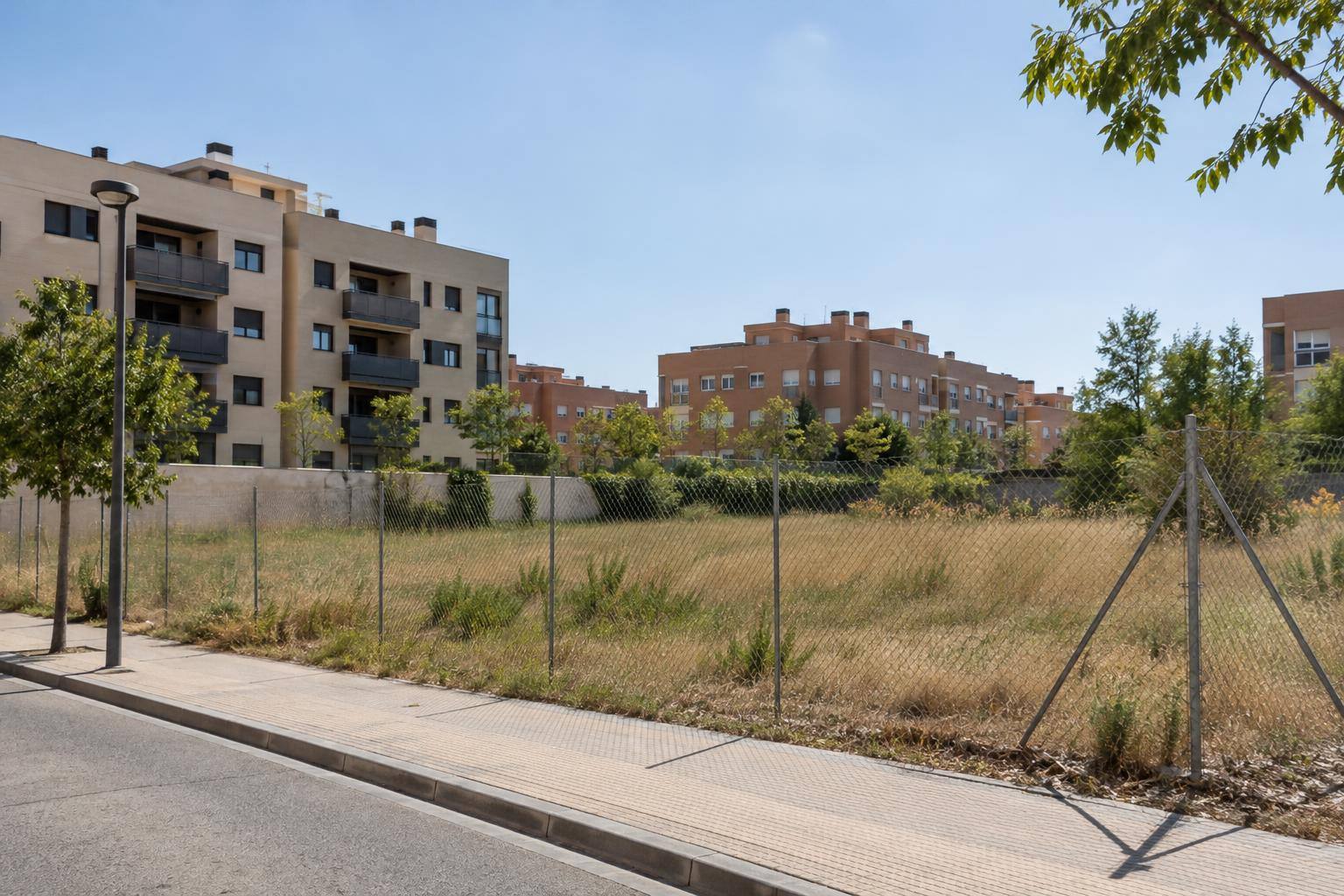 Imagen ilustrativa: Parcela urbana junto a bloques residenciales, sin personas reconocibles ni carteles identificativos.