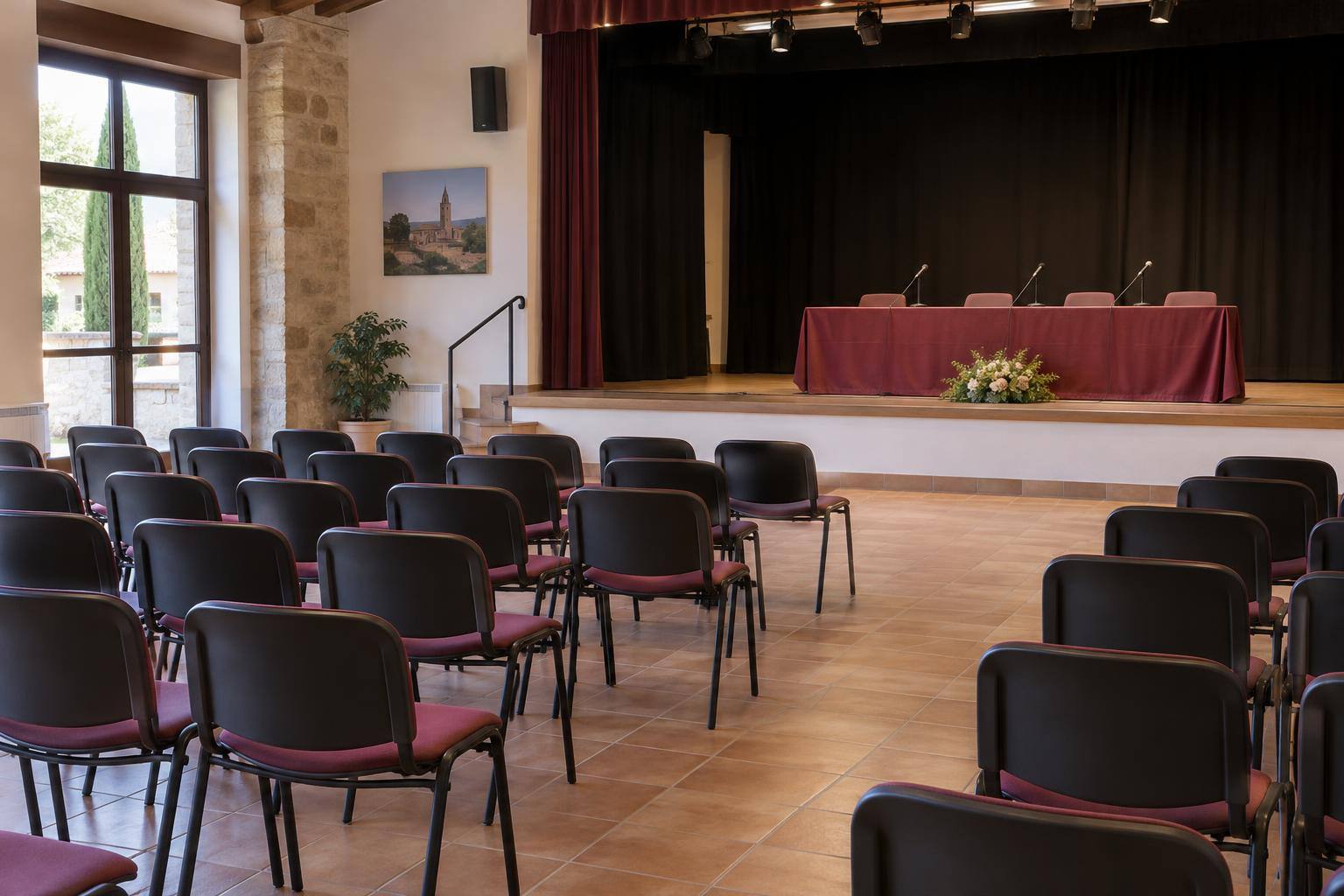 Imagen ilustrativa: Salón de actos de un centro cultural rural, con filas de sillas y una mesa con micrófonos, sin personas ni carteles identificables.