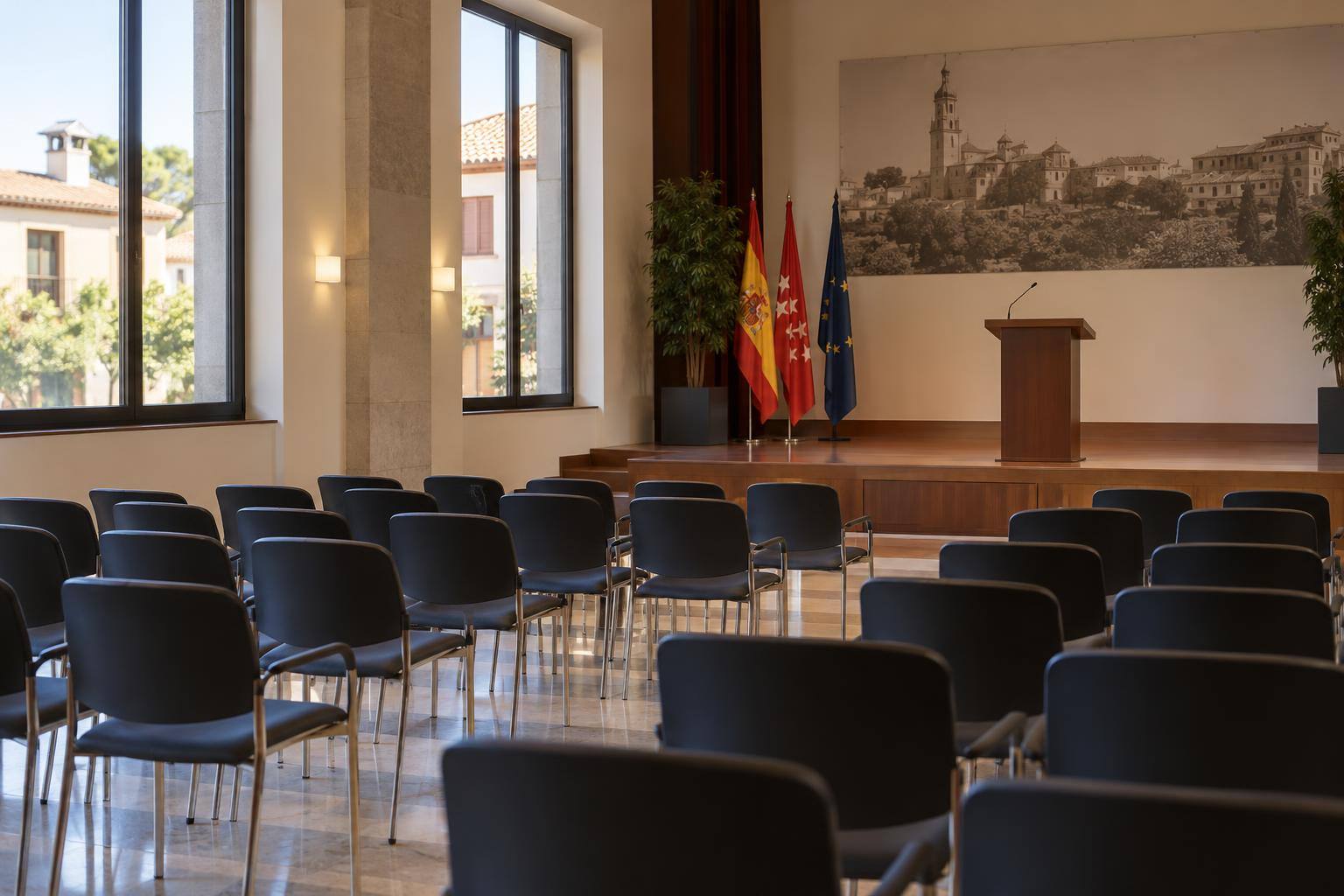 Imagen ilustrativa: Salón de actos de una institución cultural, con un atril y filas de sillas vacías.