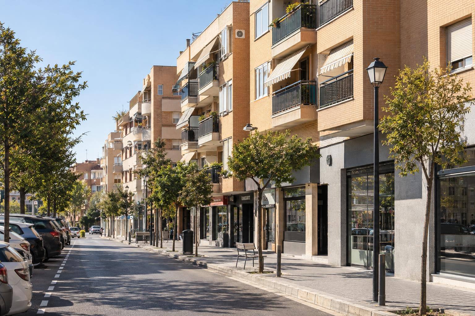 Imagen ilustrativa: bloques de viviendas y comercios de barrio en una calle urbana andaluza, sin personas reconocibles