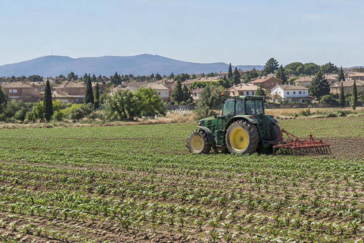 Imagen ilustrativa: Campos de cultivo con un tractor en una explotación agrícola, sin personas reconocibles