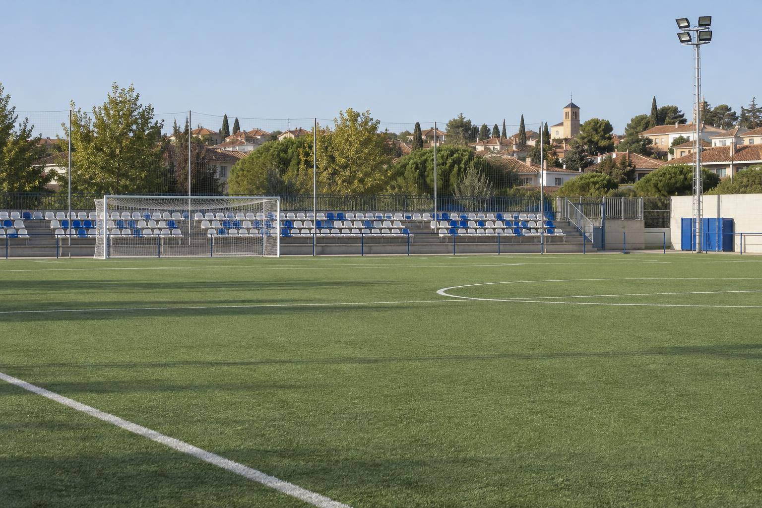 Imagen ilustrativa: Campo de fútbol municipal con una portería y gradas al fondo, sin personas reconocibles.