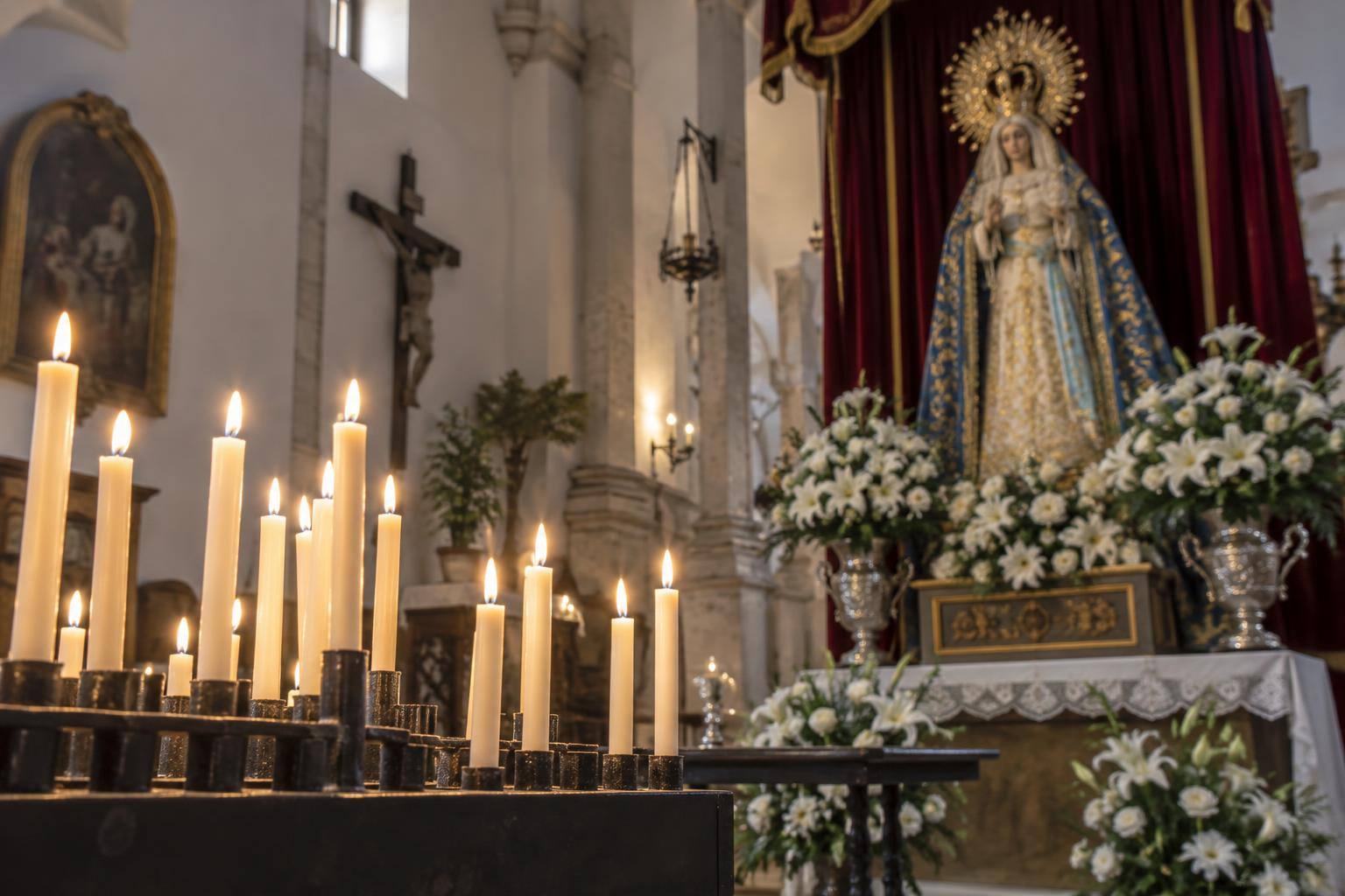 Imagen ilustrativa: Interior de una iglesia con velas encendidas y un altar mariano, sin personas reconocibles.