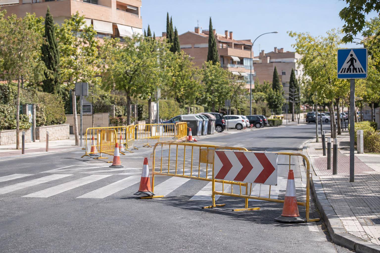 Imagen ilustrativa: Avenida urbana con vallas móviles de regulación del tráfico y conos junto a un paso de peatones, sin personas reconocibles.
