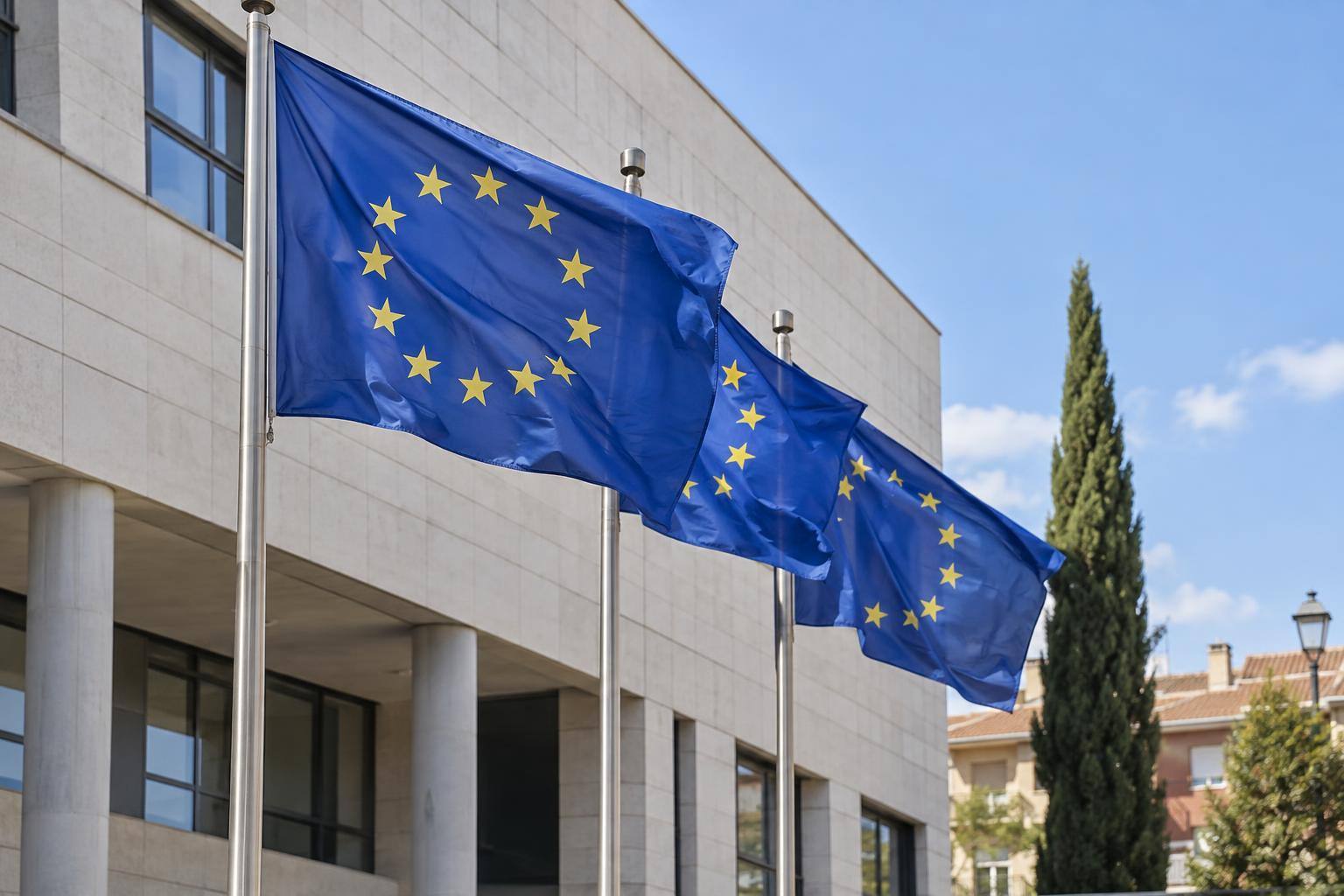 Imagen ilustrativa: Banderas de la Unión Europea ante un edificio institucional, sin personas reconocibles