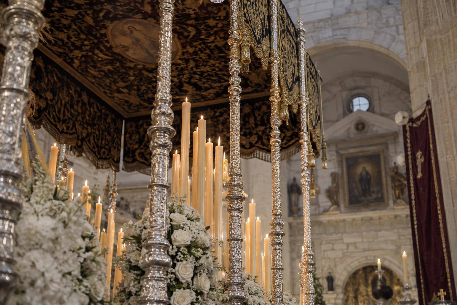 Imagen ilustrativa: Detalle genérico de los varales y la candelería de un paso de palio en el interior de una iglesia, sin personas reconocibles.