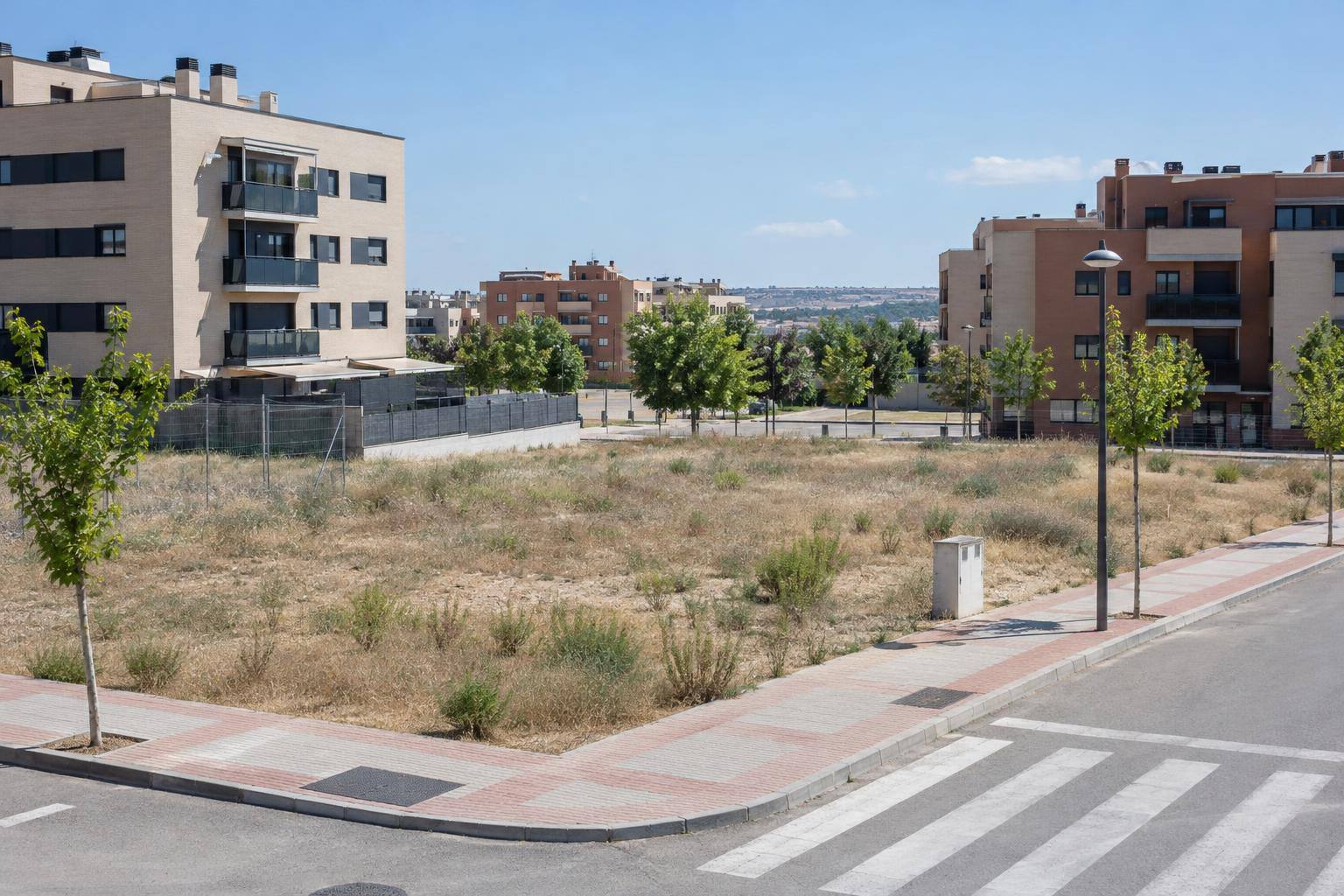 Imagen ilustrativa: Parcelas urbanas sin edificar junto a bloques residenciales y calles urbanizadas, sin personas reconocibles.