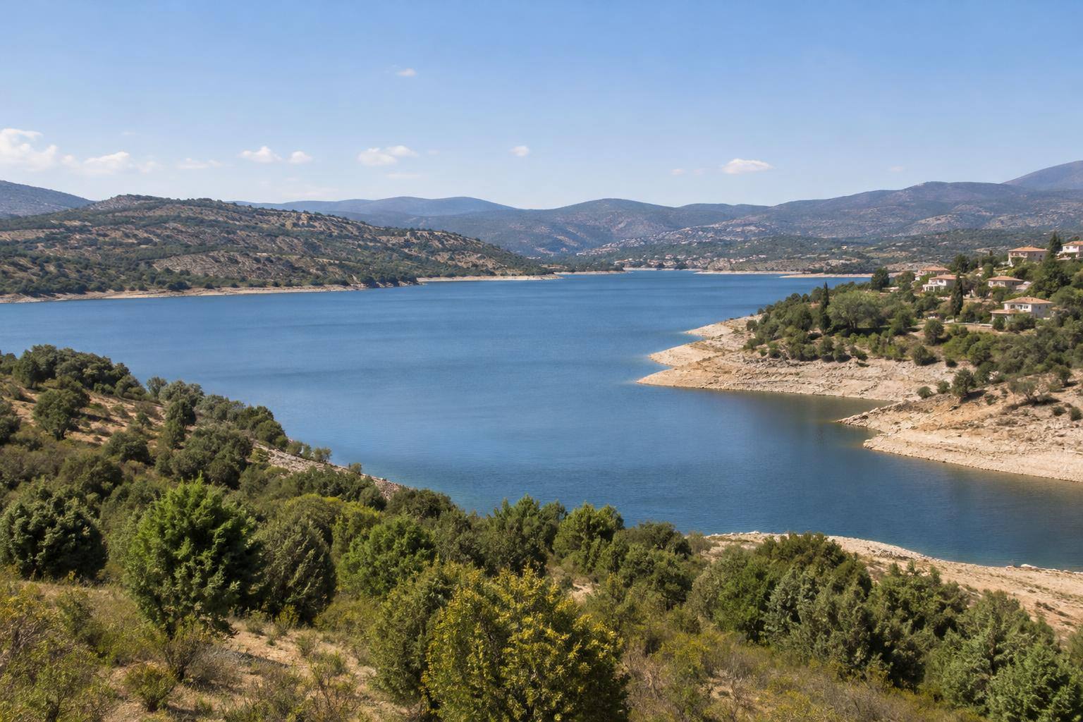 Imagen ilustrativa: Vista panorámica de un embalse entre lomas, con la lámina de agua y las orillas visibles, sin personas reconocibles.