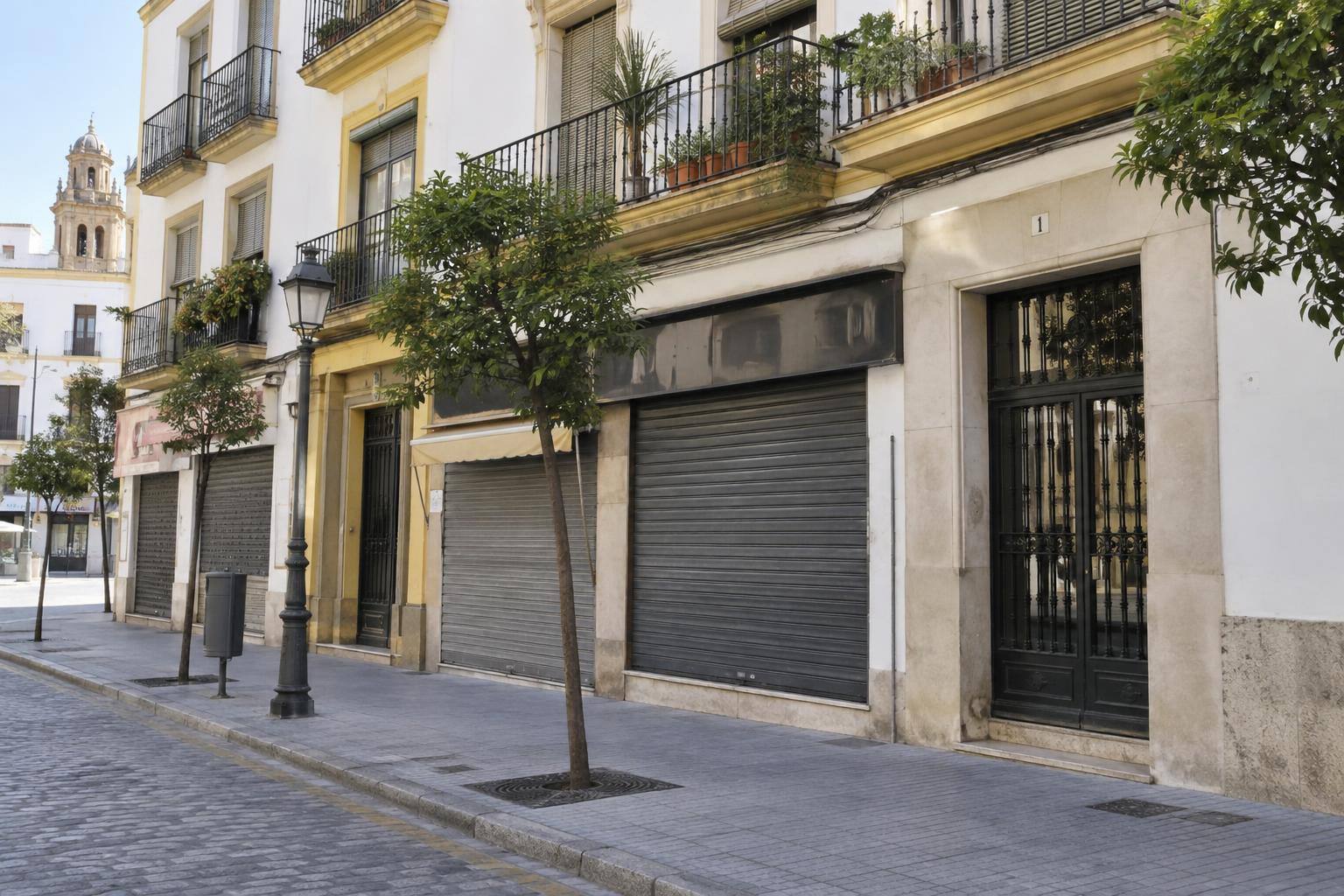 Imagen ilustrativa: Fachada de un edificio residencial con locales comerciales cerrados en la planta baja y portal comunitario, sin personas reconocibles.