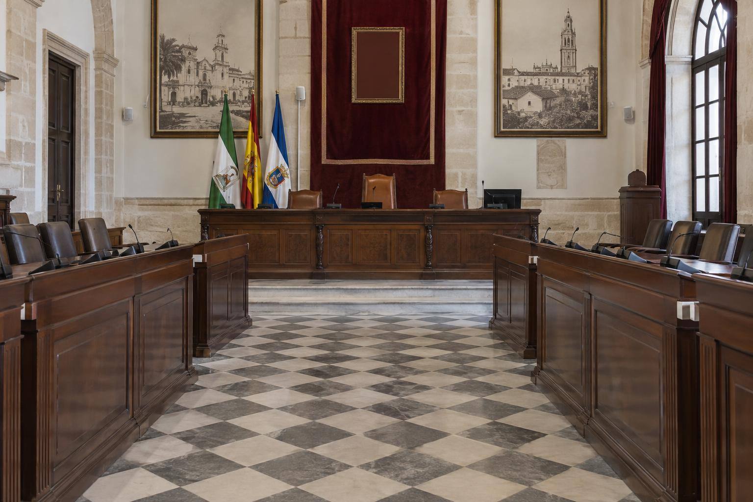 Imagen ilustrativa: Salón de plenos municipal vacío, con bancos de concejales y mesa de presidencia, sin personas ni emblemas identificables.