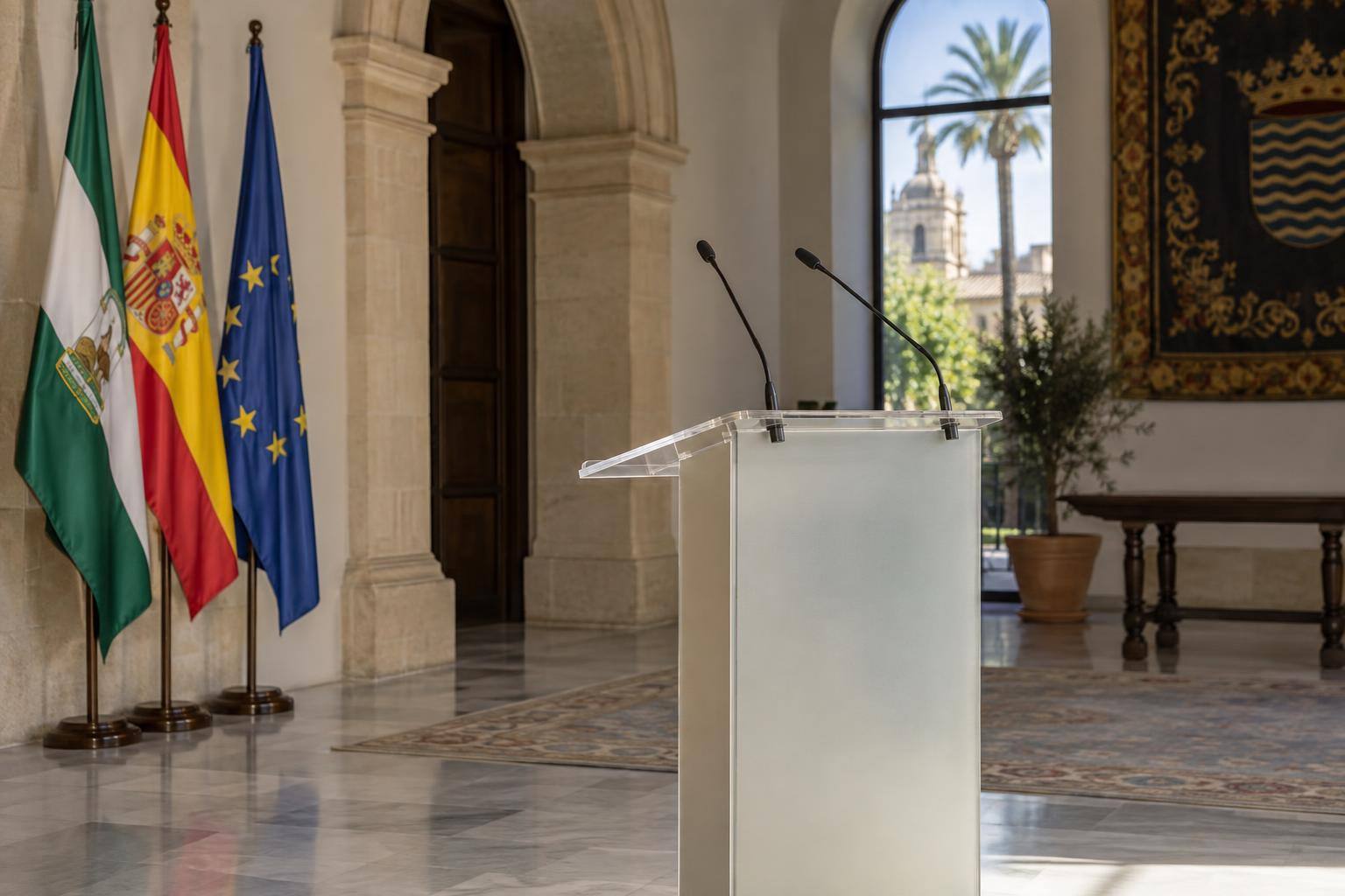 Imagen ilustrativa: Interior de una sala institucional con atril y micrófonos, sin personas ni distintivos partidistas