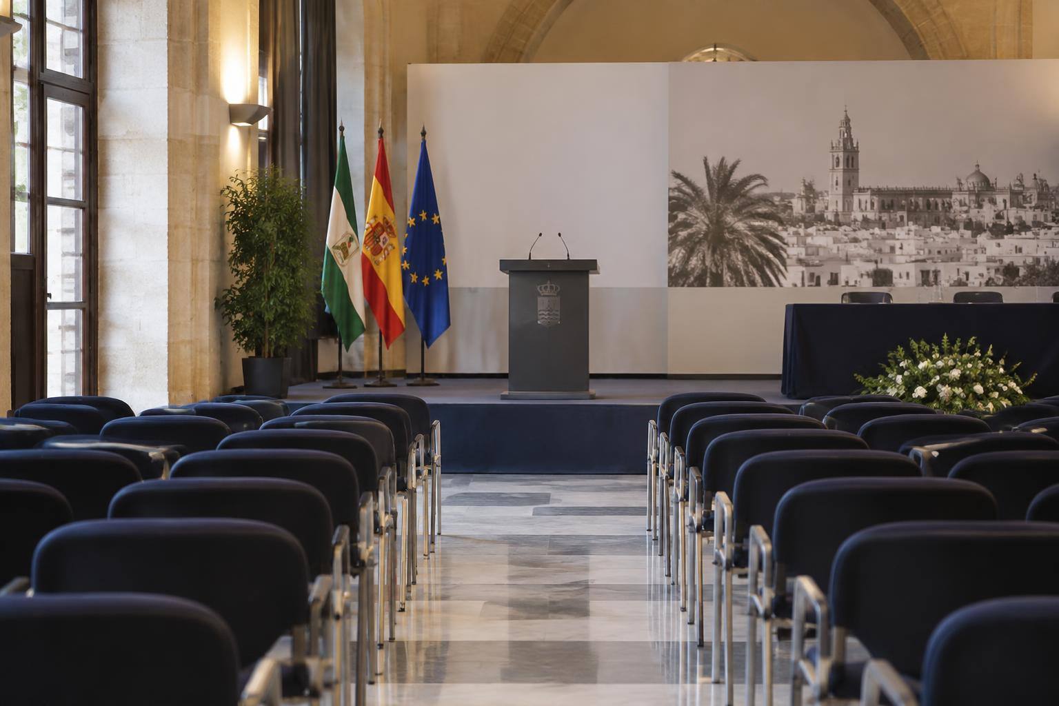 Imagen ilustrativa: Sala de actos con un atril y filas de sillas, sin personas reconocibles