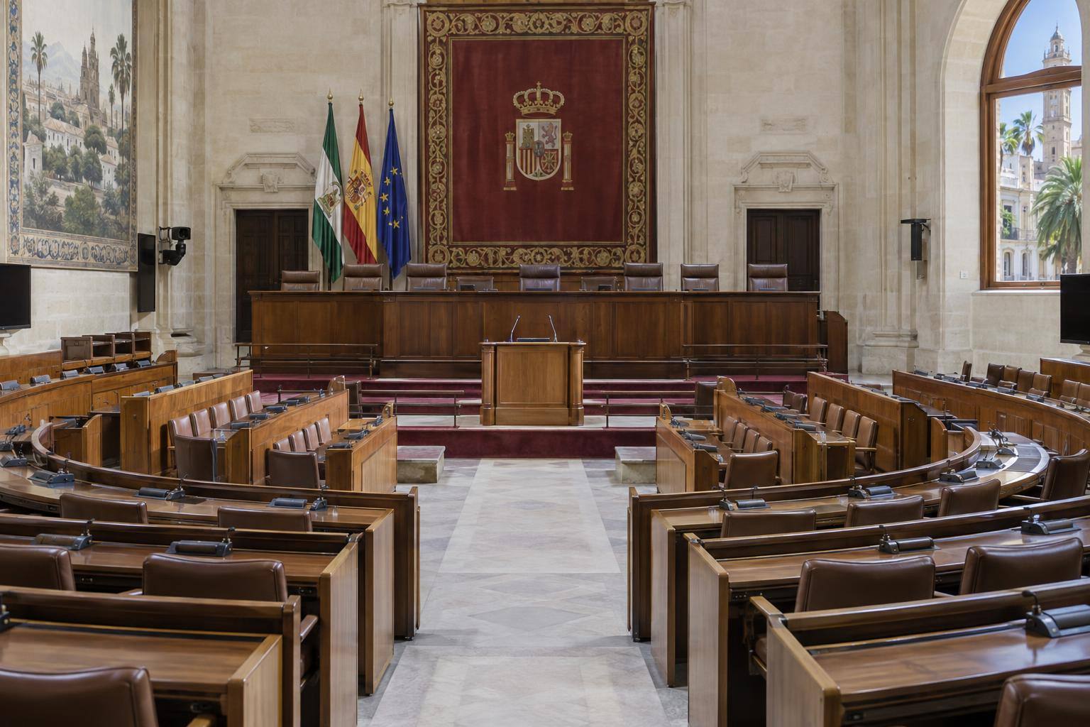 Imagen ilustrativa: Sala de un parlamento autonómico con escaños y tribuna vacíos, sin personas reconocibles