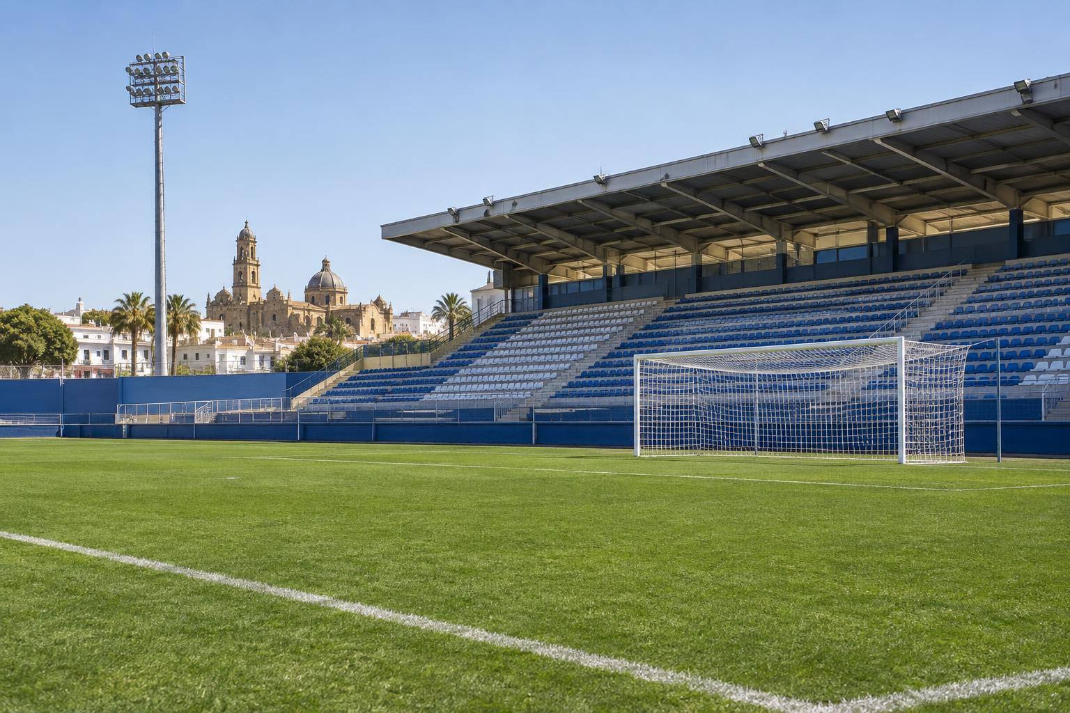 Imagen ilustrativa: Campo de fútbol con césped, una portería y gradas al fondo, sin personas reconocibles.