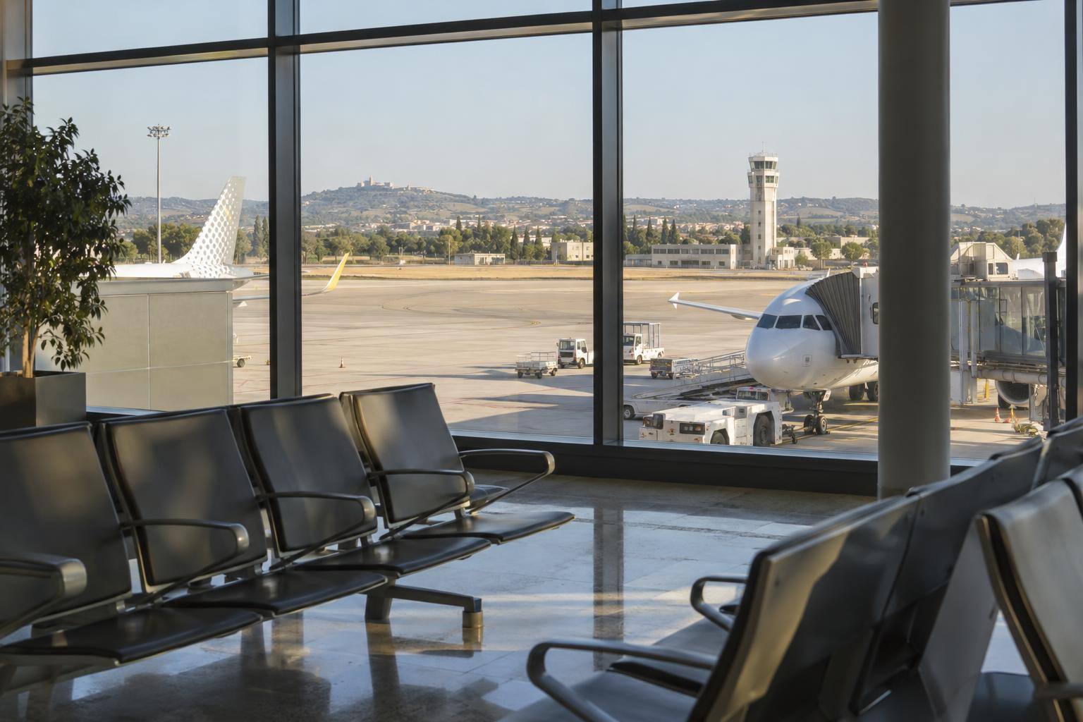 Imagen ilustrativa: Zona de embarque de un aeropuerto con ventanales hacia una plataforma de aviones, sin personas reconocibles