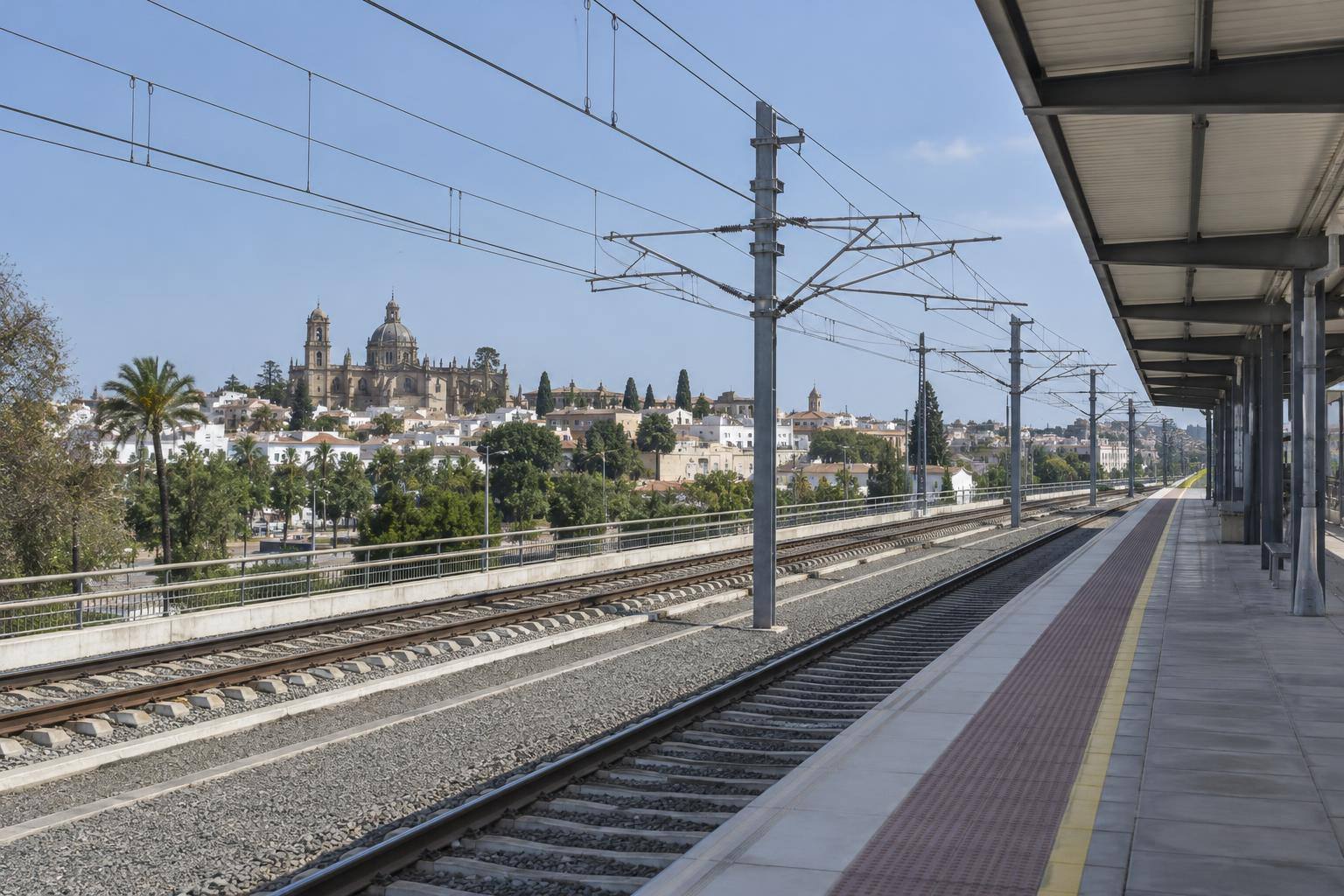 Imagen ilustrativa: Vías electrificadas de alta velocidad junto a un andén ferroviario, sin personas reconocibles.
